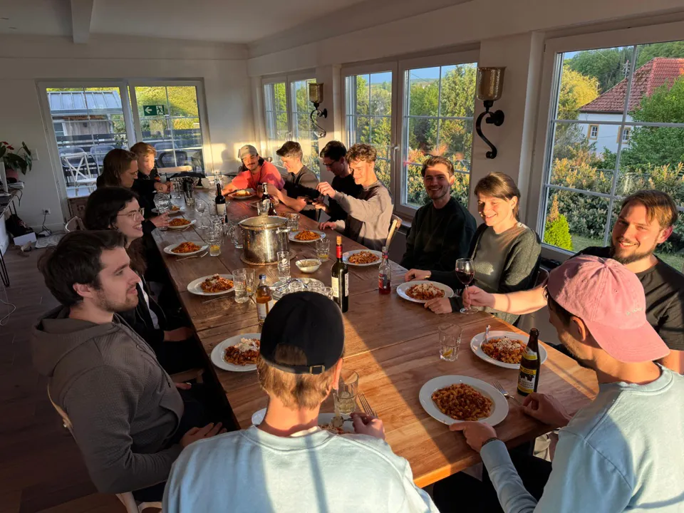 Das Team beim Abendessen an einer langen Tafel in der Abendsonne