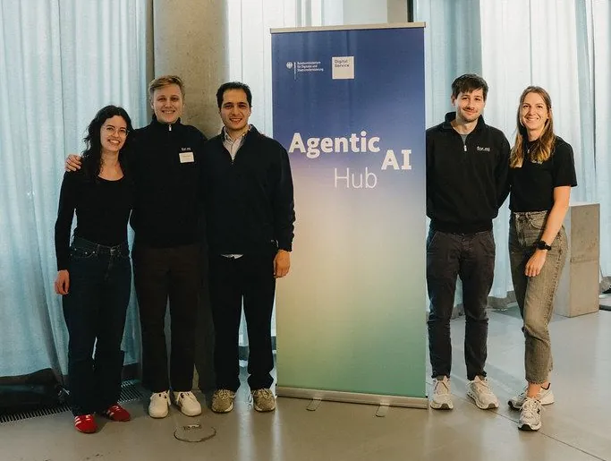Fünf Personen stehen neben einem Banner des Agentic AI Hub