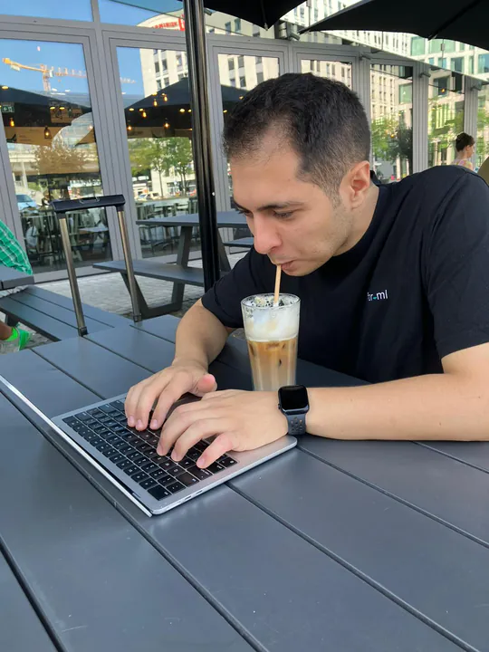 Kollege arbeitet im Café am Laptop und trinkt einen Eiskaffee