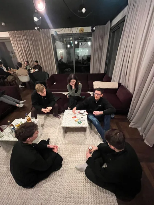 Fünf Kolleginnen und Kollegen sitzen beim Spieleabend um einen Couchtisch