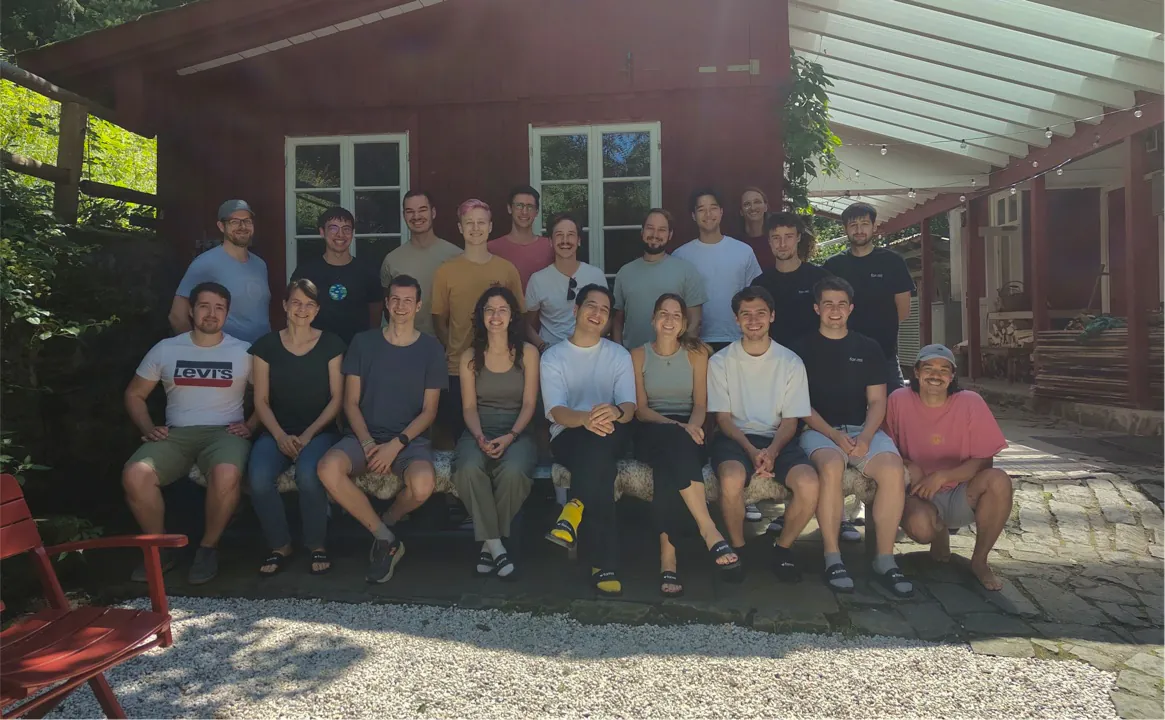 Gruppenfoto des Teams vor einer Holzhütte im Grünen